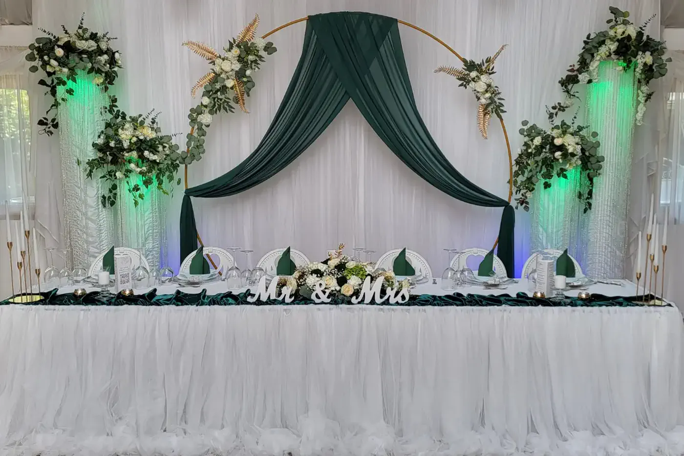 Brauttisch mit goldenem Ring, dunkelgrüner Draperie und weißen Blumen